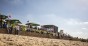Menschen auf dem Unite Sommerfest sitzen in Sonnenstühlen am Strand. Im Hintergrund steht eine Bühne